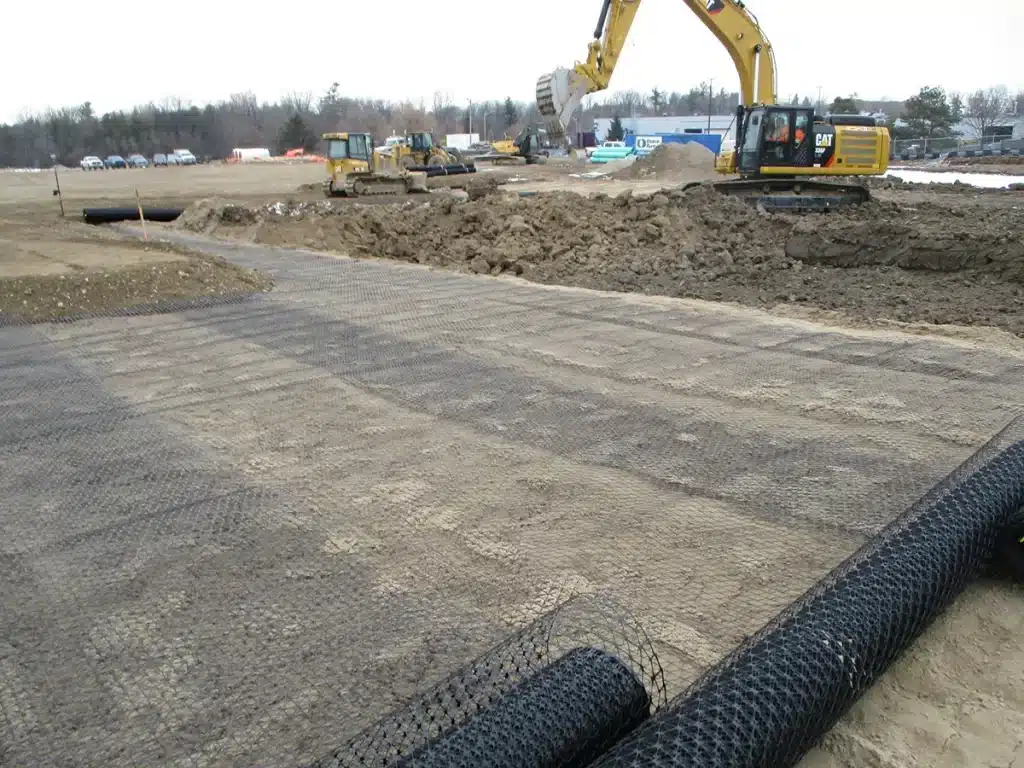 Instalación de geomalla biaxial en base de carretera para refuerzo y estabilización del suelo