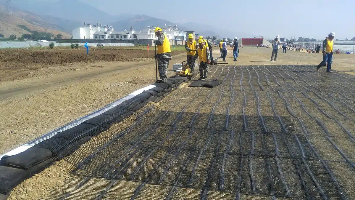 Instalación de geomalla uniaxial reforzando el suelo en un proyecto de construcción