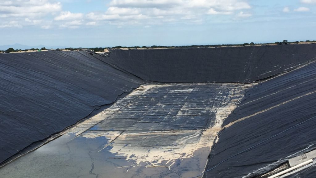 Canal hidráulico con instalación de geotextil para control de filtración y protección del terreno en una obra de ingeniería hidráulica.