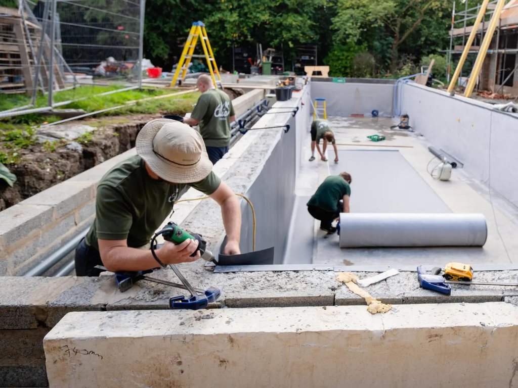 Instalación de geomembrana para piscinas durante la impermeabilización de una estructura recreativa de concreto.